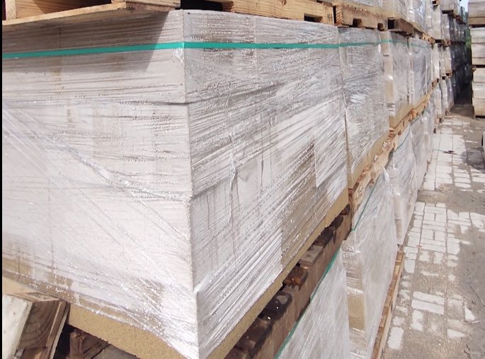 Estibas de bloques forradas con plástico estirable en el patio de una planta, con el film ajustado hasta la base del pallet y condensación en su cara interior