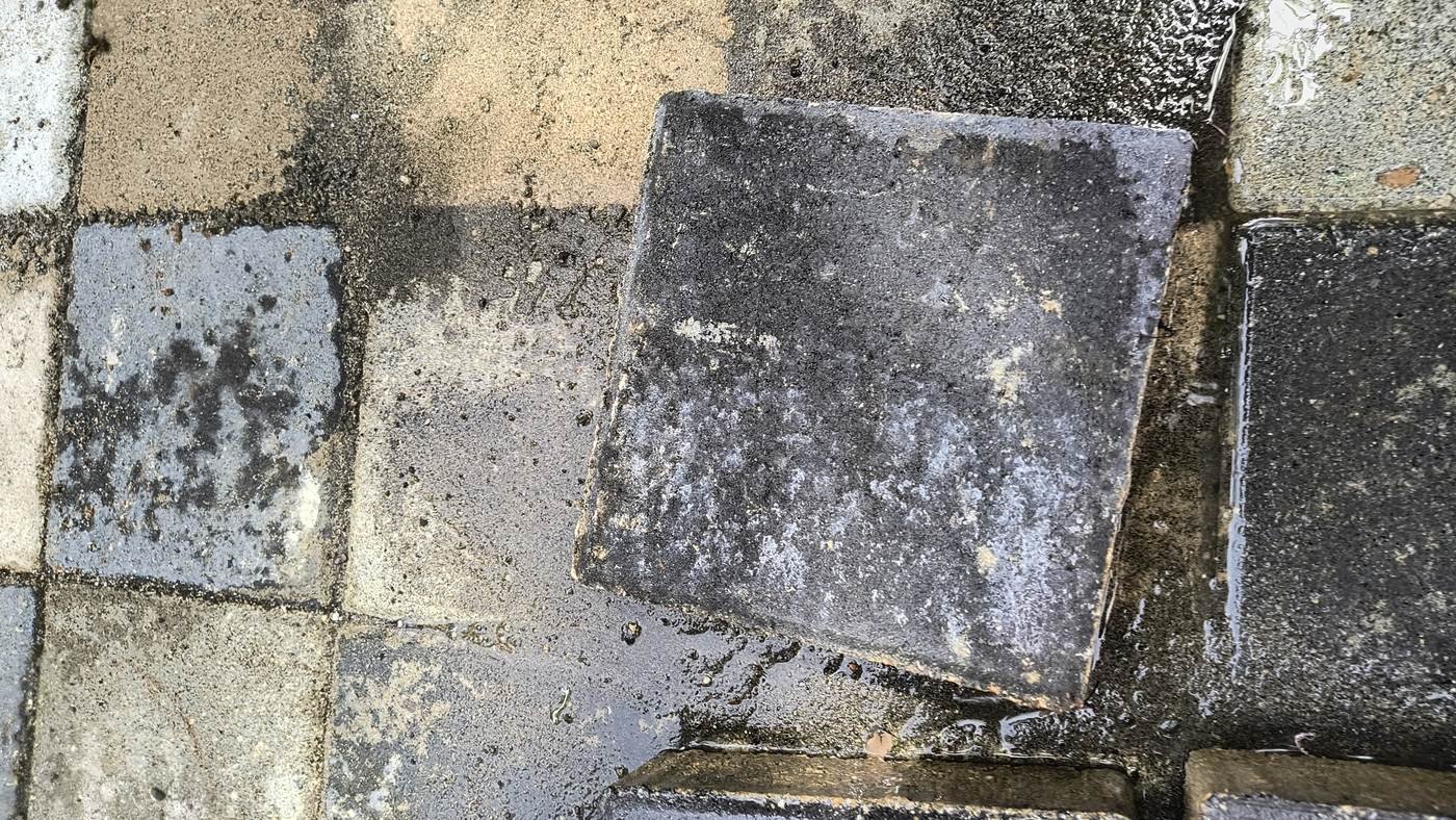 Pieza de concreto oscura con velo blanco, rodeada de piezas claras del mismo paño que muestran el mismo depósito con mucha menos visibilidad
